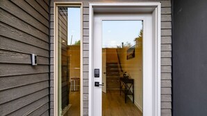 A modern house with a wooden exterior, a white door, and a visible staircase leading to an upper level. - Urban Roosevelt/Greenlake Getaway (Seattle)