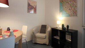 A small, cozy room with a round table, a single chair, a map on the wall, and a lamp on a side table. - Barbadori Suite (Florence)