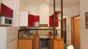 A compact kitchen with a microwave, stove, and wooden cabinets. - Barbadori Suite (Florence)