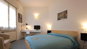A bedroom with a bed, a desk, a chair, a computer, and a television. - Barbadori Suite (Florence)