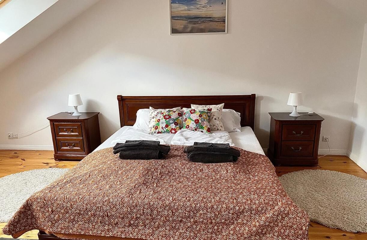 Une chambre à coucher avec un lit en bois, deux tables de chevet avec des lampes, un coussin à motifs floraux et une couvre-lit à motifs.