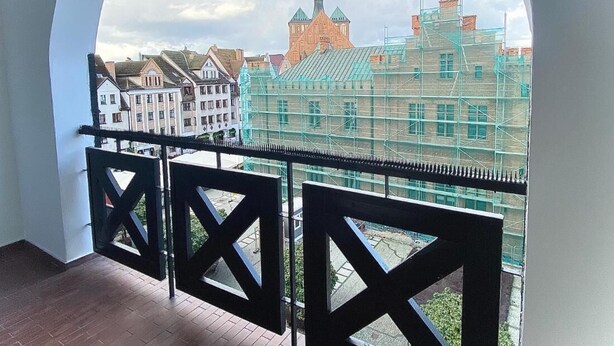 A balcony with a view of historic buildings and scaffolding. - Penthouse in the old Citycenter (Kolobrzeg)
