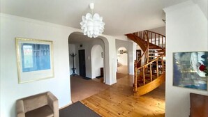 A spacious living area with a wooden floor, a staircase, and a chandelier. - Penthouse in the old Citycenter (Kolobrzeg)
