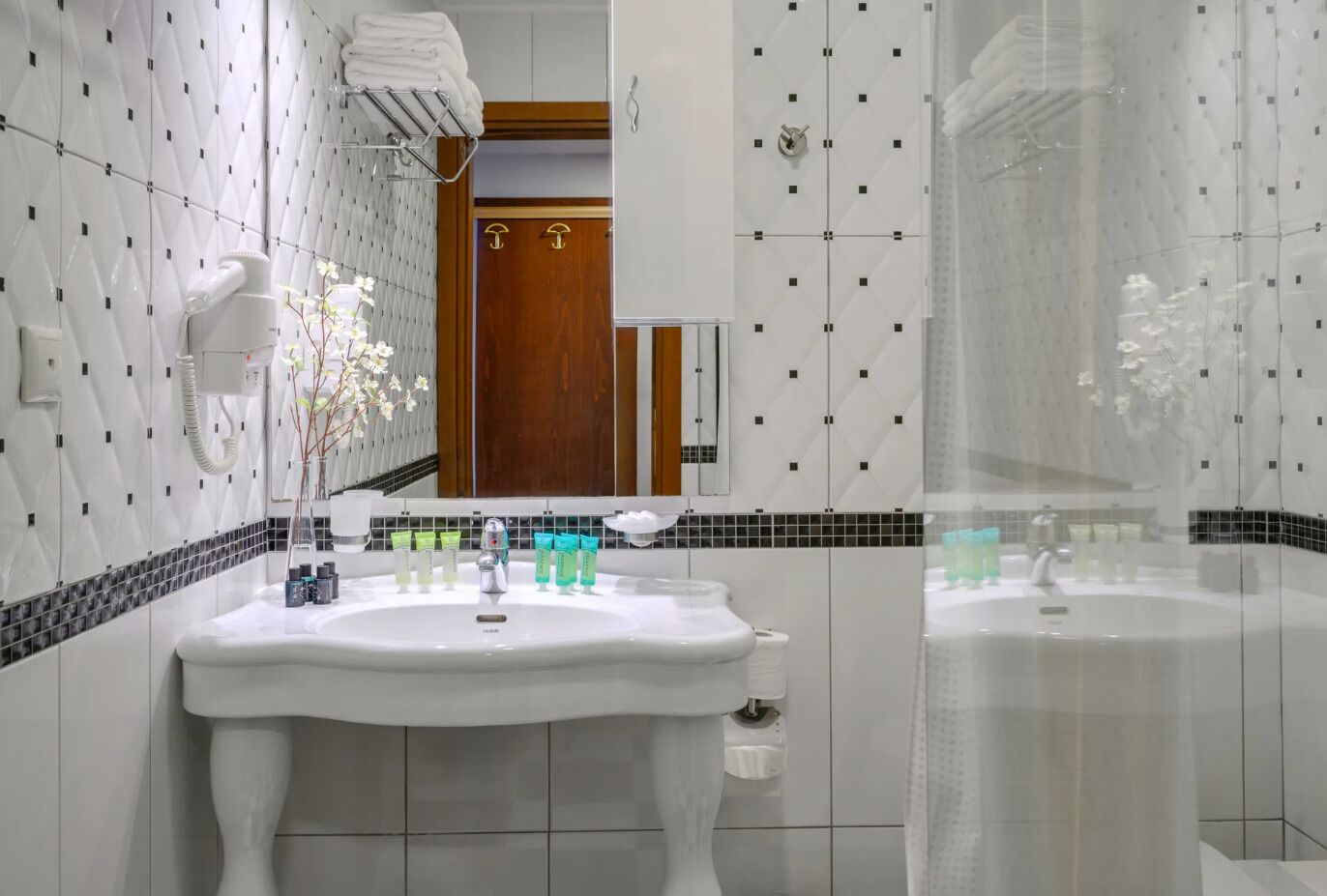 Ein modernes Badezimmer mit einem weißen Waschbecken, zwei Spiegeln und einer Dusche.