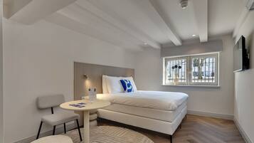 A modern bedroom with a bed, a small round table, a chair, and a window with a view.