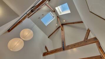 A high ceiling with exposed wooden beams, skylights, and hanging spherical light fixtures.