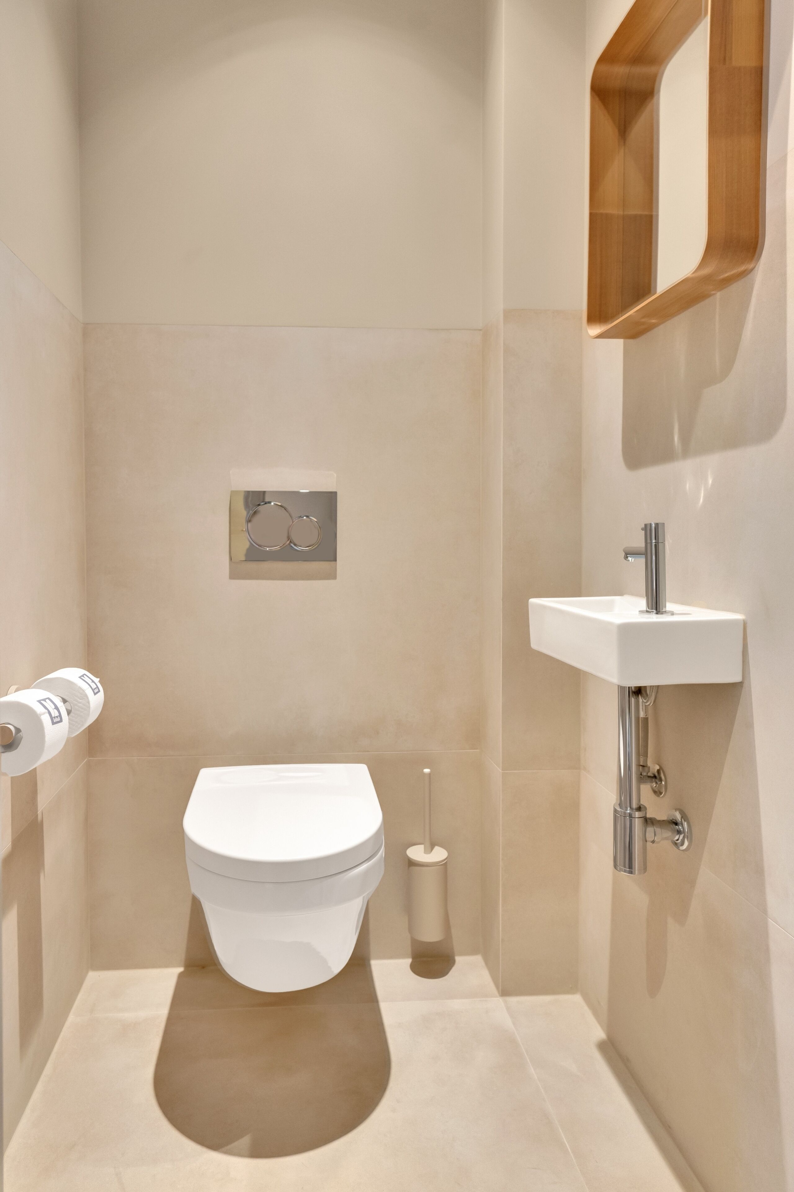 Ein modernes Badezimmer mit Toilette, Waschbecken und Spiegel.
