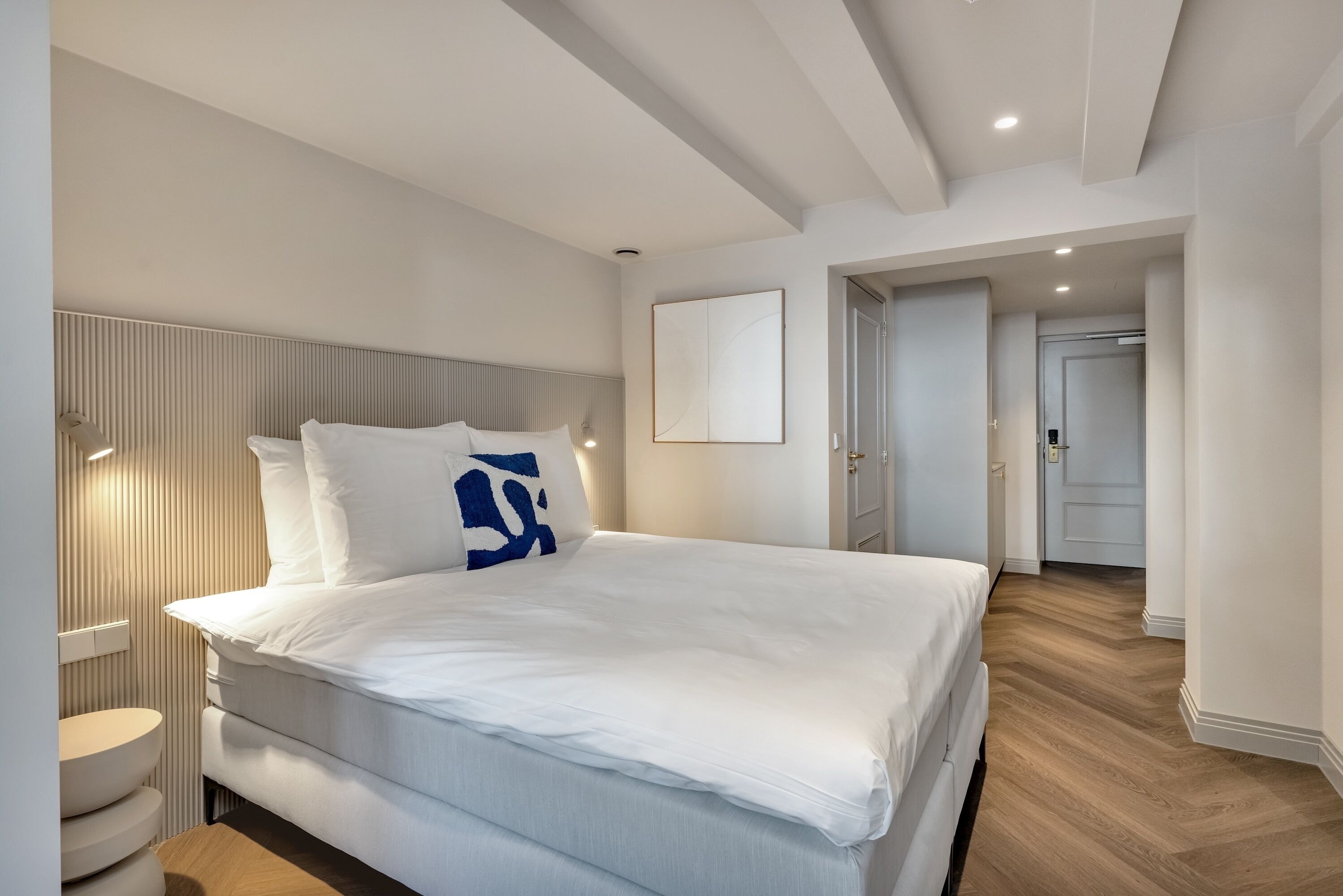 Ein modernes Schlafzimmer mit einem großen Bett, einem Nachttisch und einer Wandlampe.