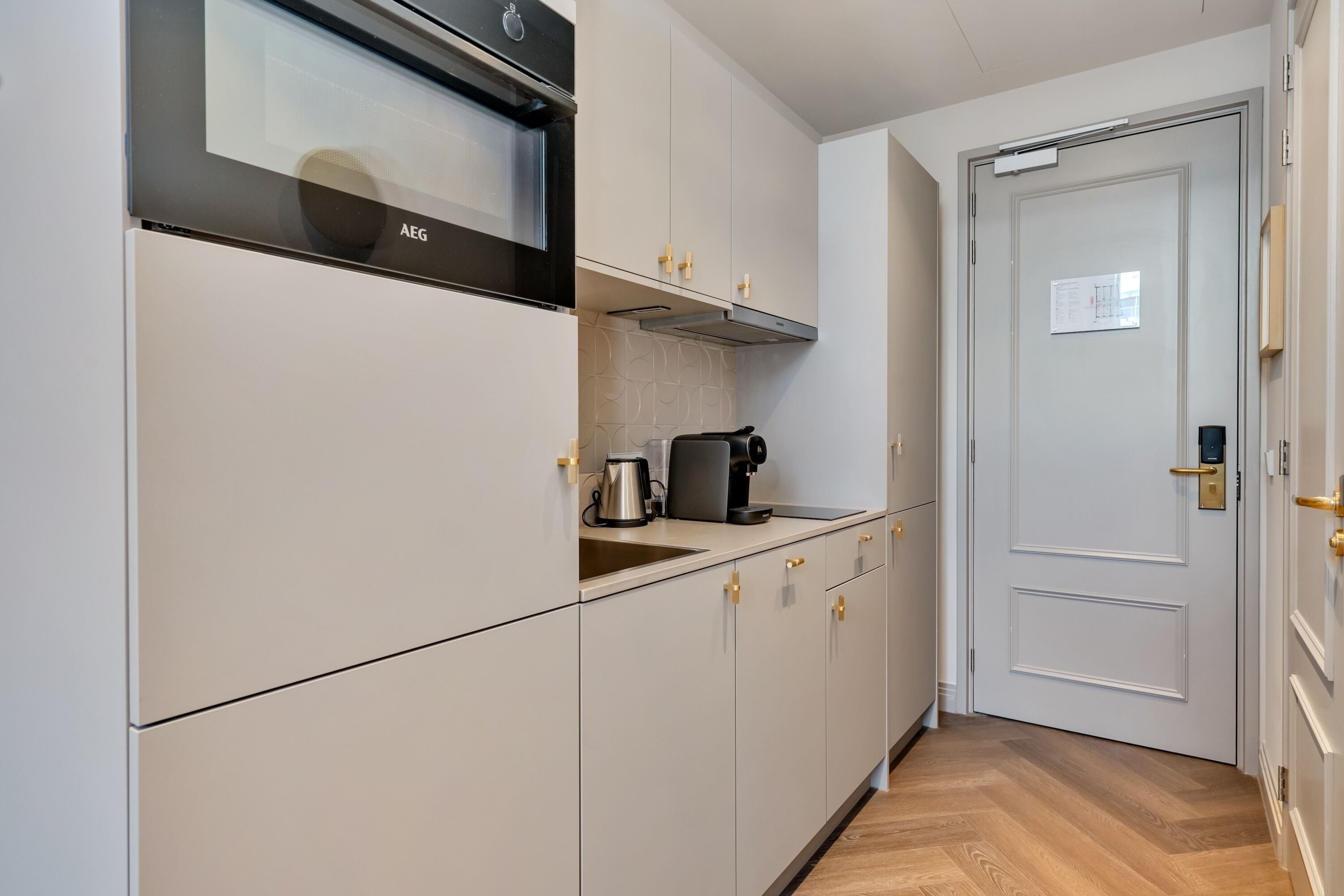 Une cuisine avec des armoires blanches, une hotte de cuisinière en acier inoxydable et une machine à café.