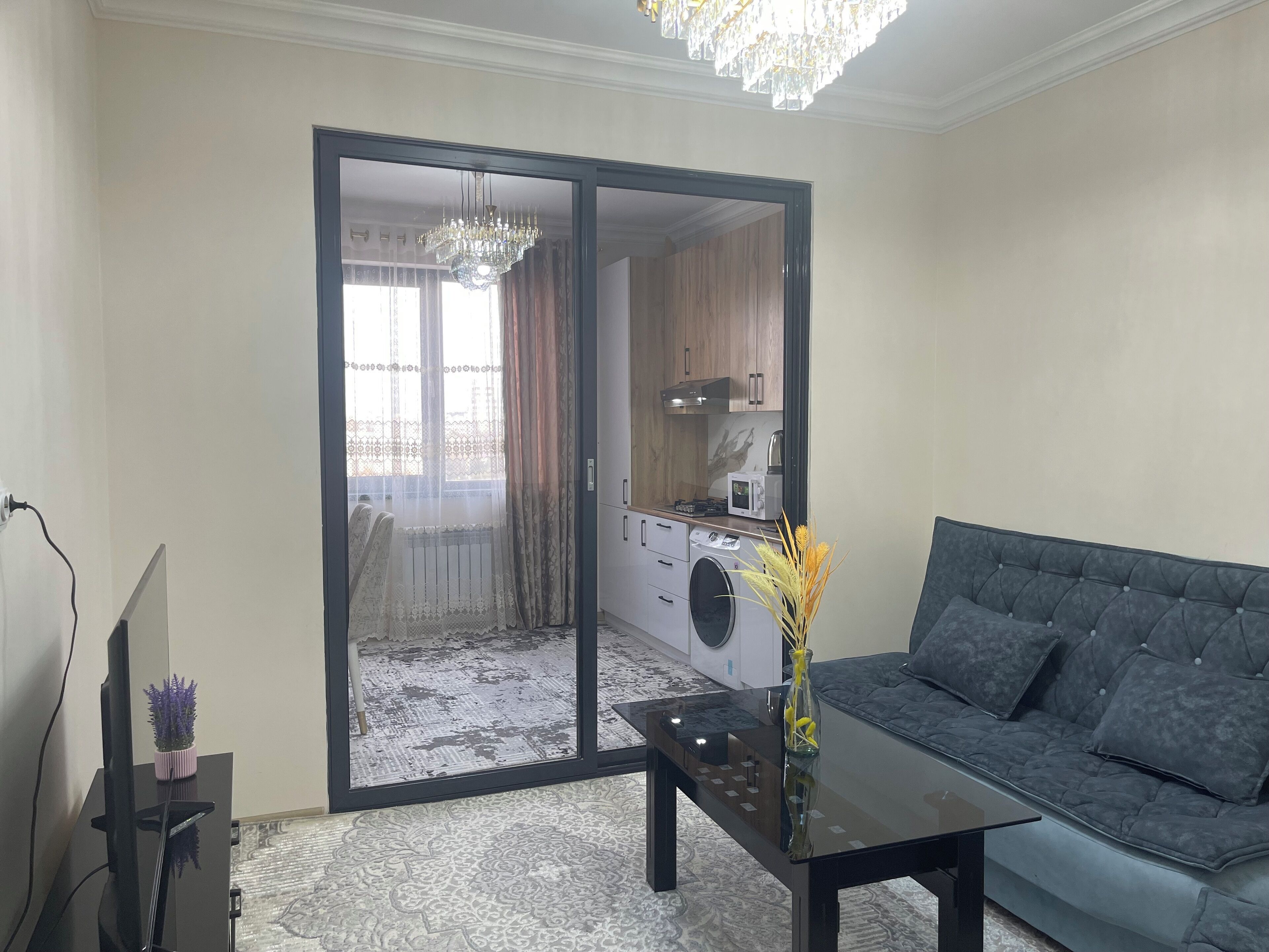 Olohuoneessa on sohva, sohvapöytä, televisio ja liukuovet, joista pääsee keittiöön.