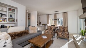 A modern living room with a grey sofa, patterned armchairs, a wooden coffee table, and a bookshelf. - Condo with Fireplace and Mountain Views! Close to Sun Valley Village! (Sun Valley)