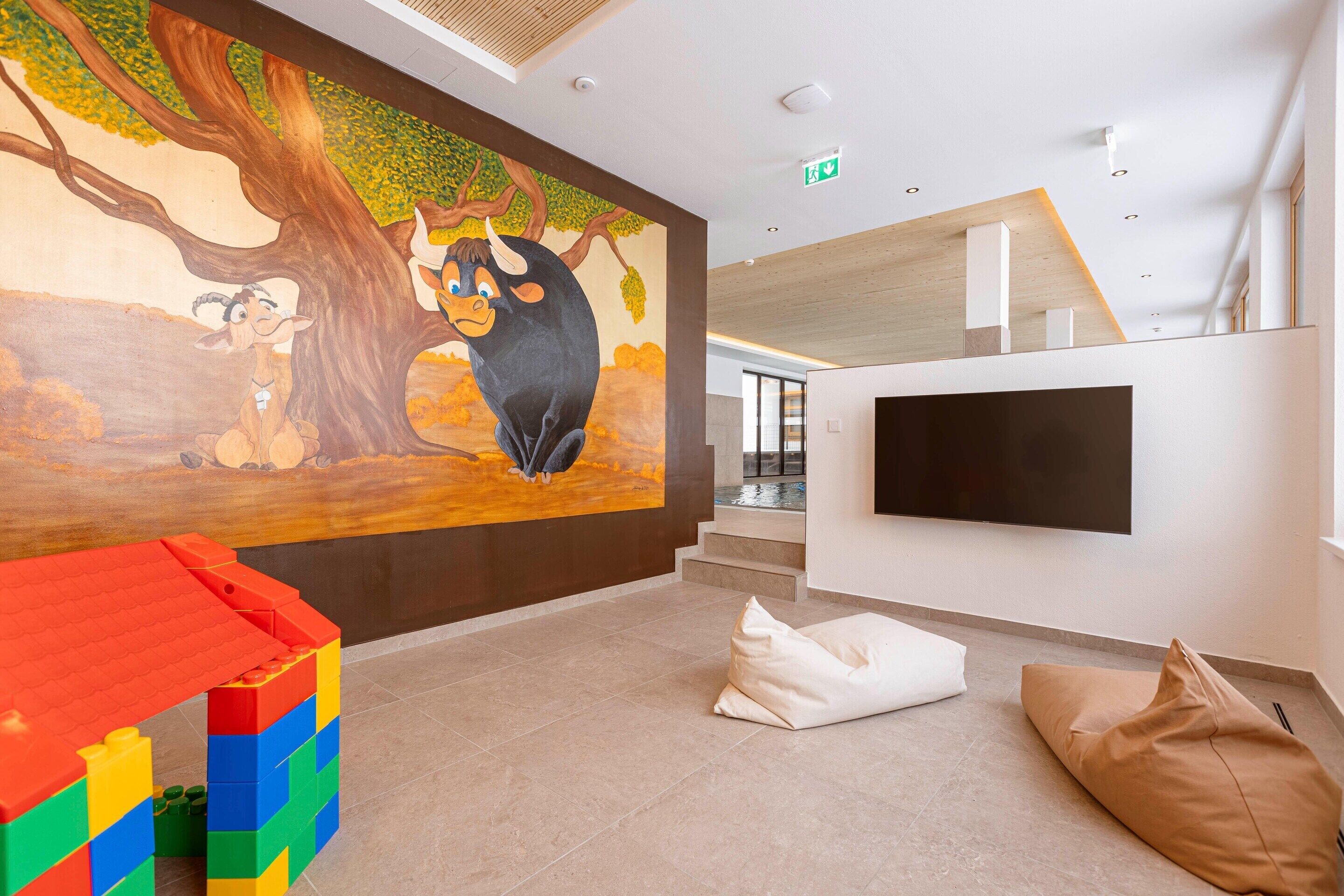 Un interior moderno con un mural, una zona de juegos y un televisor de pantalla plana.