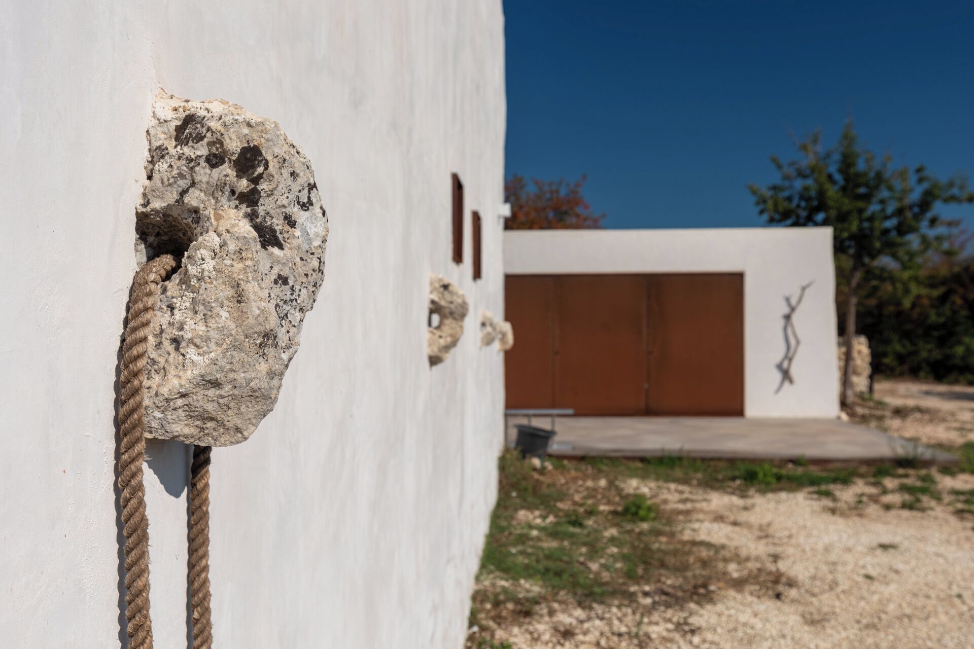 A building with a white exterior, a brown door, and a metal sculpture on the wall.