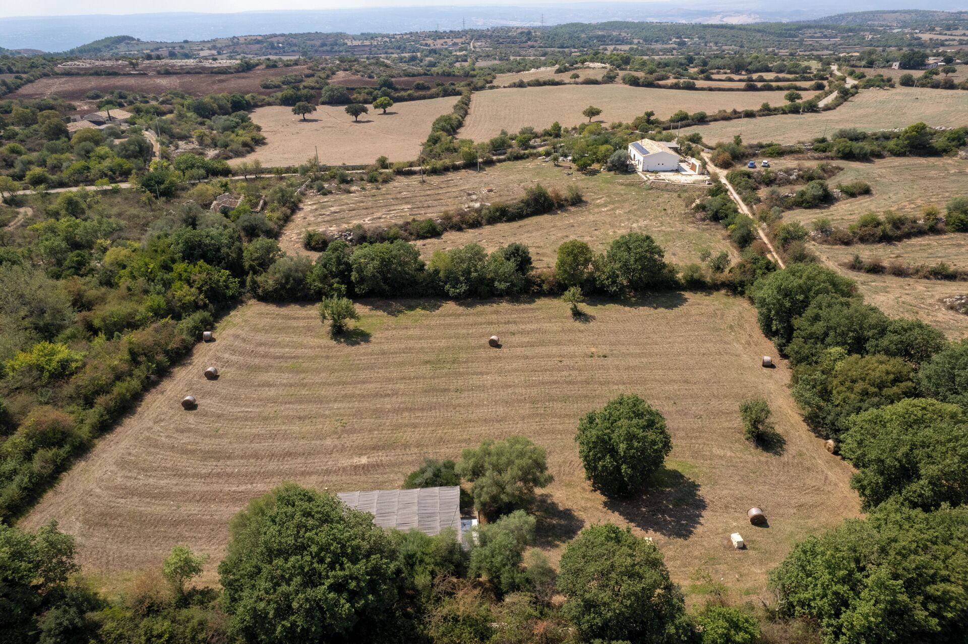 An aerial view of a rural landscape with fields, trees, and a farmhouse.