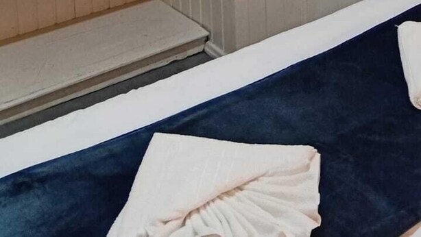 A room with a bunk bed, a small shelf with folded blankets, a hanging towel, and a round mirror on the wall. - Pousada Canto da Vigia (Penha)