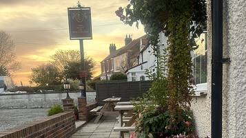 Un patio con pared de ladrillo, un letrero que dice "The Duke of Wellington" y mobiliario para estar al aire libre.