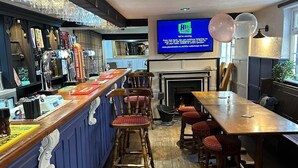 A bar area with a long counter, multiple stools, a television screen, and a fireplace. - Wellington Studio, Sleeps 2, Pets Ok, Free Parking (Northallerton)