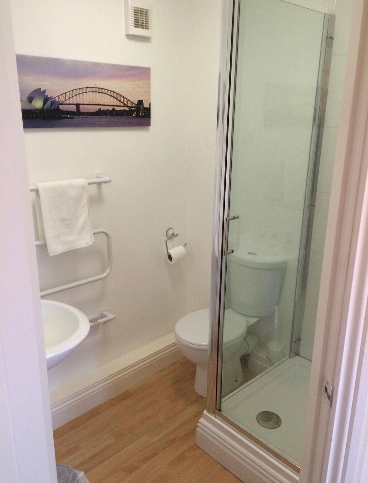 A bathroom with a glass-enclosed shower, a toilet, and a sink.