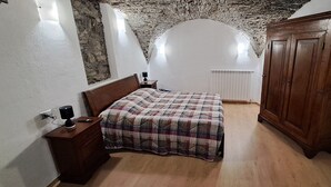 Ein Schlafzimmer mit einem hölzernen Bett, einem Nachttisch, einem Kleiderschrank und einer Steindecke.