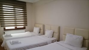 A hotel room with three single beds, each with a white headboard and pillow, and a window with horizontal blinds. - Snow Life Hotel Sarıkamış (Sarikamis)