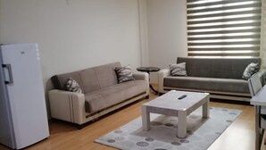 A living room with a sofa, a coffee table, and a refrigerator. - Snow Life Hotel Sarıkamış (Sarikamis)