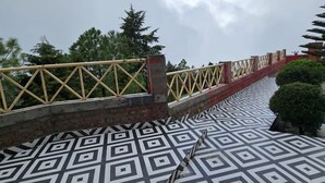 Un puente con suelo de diseño geométrico, barandilla amarilla y pared de ladrillo.