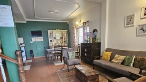Una sala de estar con un sofá, sillas, una mesita de centro, un cofre de madera y una zona de comedor con mesa y sillas.