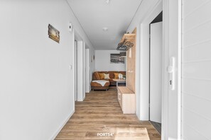 Un pasillo con piso de madera que conduce a una sala de estar con un sofá y una mesita.