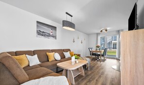 Una sala de estar moderna con un sofá marrón, una mesa de centro de madera y un comedor con mesa y sillas.