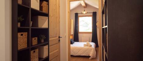 Ein Schlafzimmer mit einem Bett, einer Holztür und einem Regal mit Körben.
