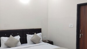 Uma cama bem arrumada com cabeceira de madeira, mesa de cabeceira com controle remoto e ventilador de teto.