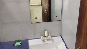 Casa de banho com uma pia branca, um espelho e chão azul.