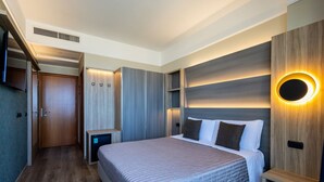 A modern bedroom with a large bed, built-in wardrobe, and a wall-mounted circular light fixture. - Hotel Palm Beach (Rimini)