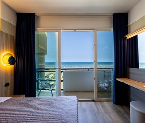 A modern hotel room with a large bed, a balcony with a glass door, and a view of the ocean. - Hotel Palm Beach (Rimini)
