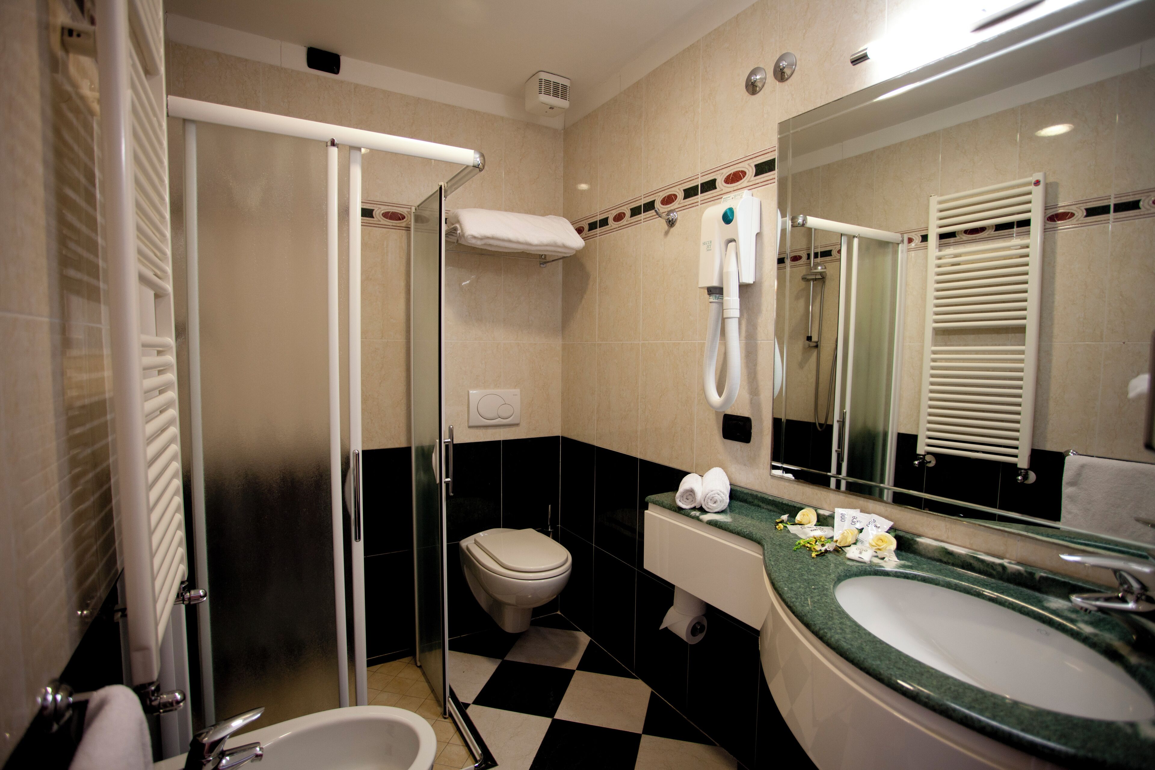 A bathroom with a shower, toilet, sink, and a large mirror.