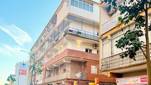 A multi-story building with balconies, a pedestrian crossing, and a car parked on the street. - Aperol Apartment - Malaga (Málaga)