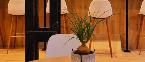 Un salón de conferencias con una mesa de madera, sillas, un reloj decorativo y una planta en maceta.