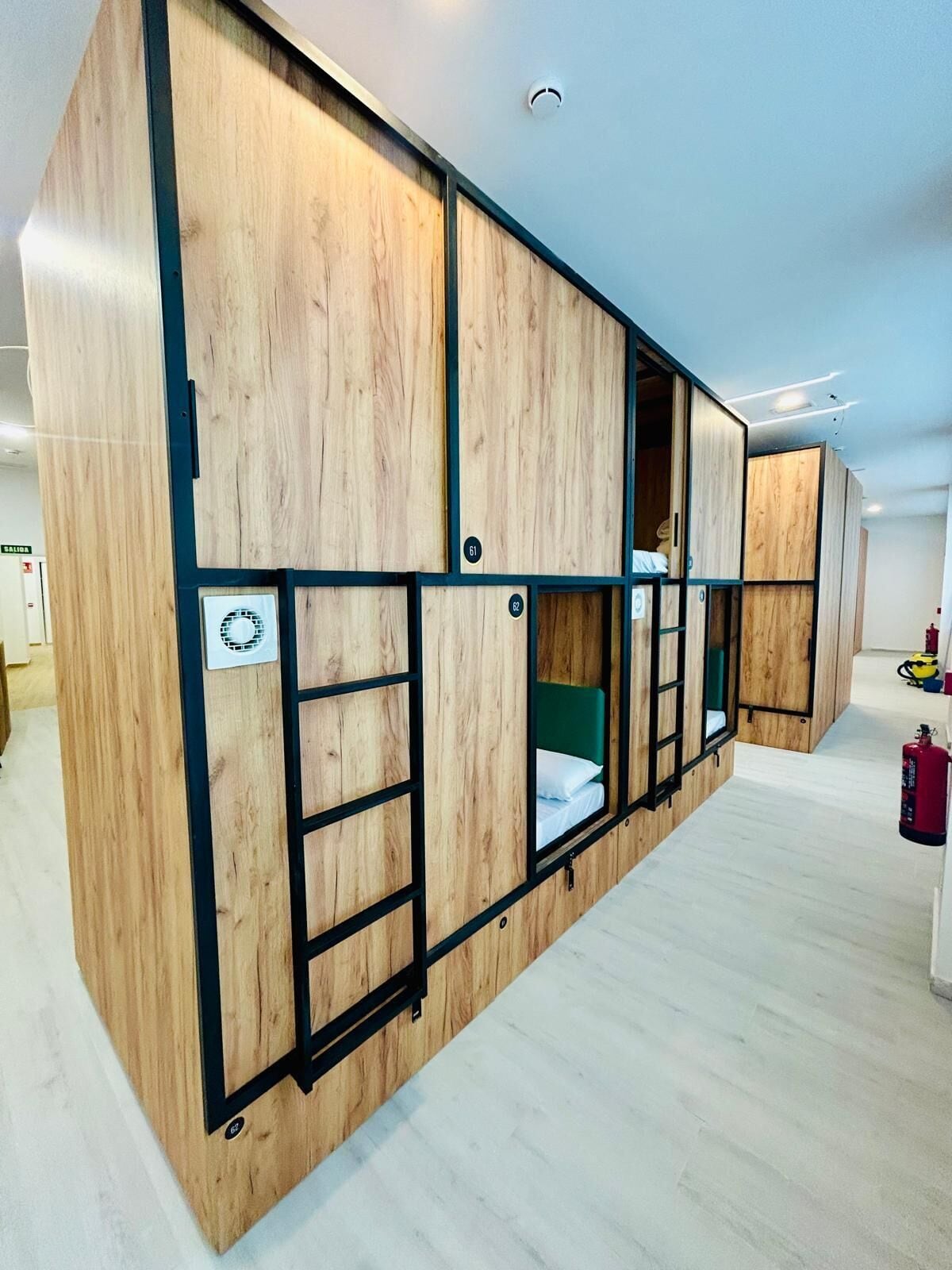 Un hotel moderno, con varias habitaciones, paneles de madera y detalles en metal negro.