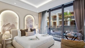 Een moderne hotelkamer met een groot bed, een glazen tafel met uitzicht en een balkon met zitplaatsen buiten.