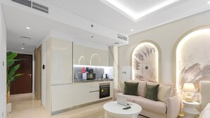 Een moderne woonkamer met een bank, salontafel en een keukenhoek met inbouwapparatuur.