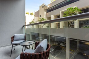 Een modern buitgedeelte met een glazen balustrade, twee comfortabele stoelen en een kleine ronde tafel.