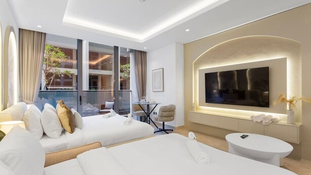 Een moderne hotelkamer met twee bedden, een televisie, een klein tafeltje en een balkon met uitzicht op het gebouw.