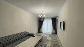 A modern living room with a grey sofa, a small table, and a TV mounted on the wall. - Chaqar 317 (Tashkent)