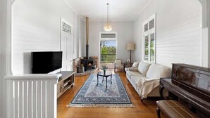 Un salon avec une cheminée, un téléviseur, un canapé, une table basse et un piano.