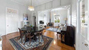Un salon spacieux avec une grande table ronde, un piano et une cheminée.