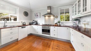 Une cuisine moderne avec des meubles blancs, une hotte en acier inoxydable et un plancher en bois.