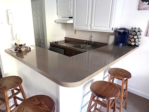 A kitchen with a central island, bar stools, a coffee maker, and a bottle of hand soap. - Ski On/Off Winter Mountain Suite Jiminy Peak-- Sleeps4- Home Away From Home (Hancock)