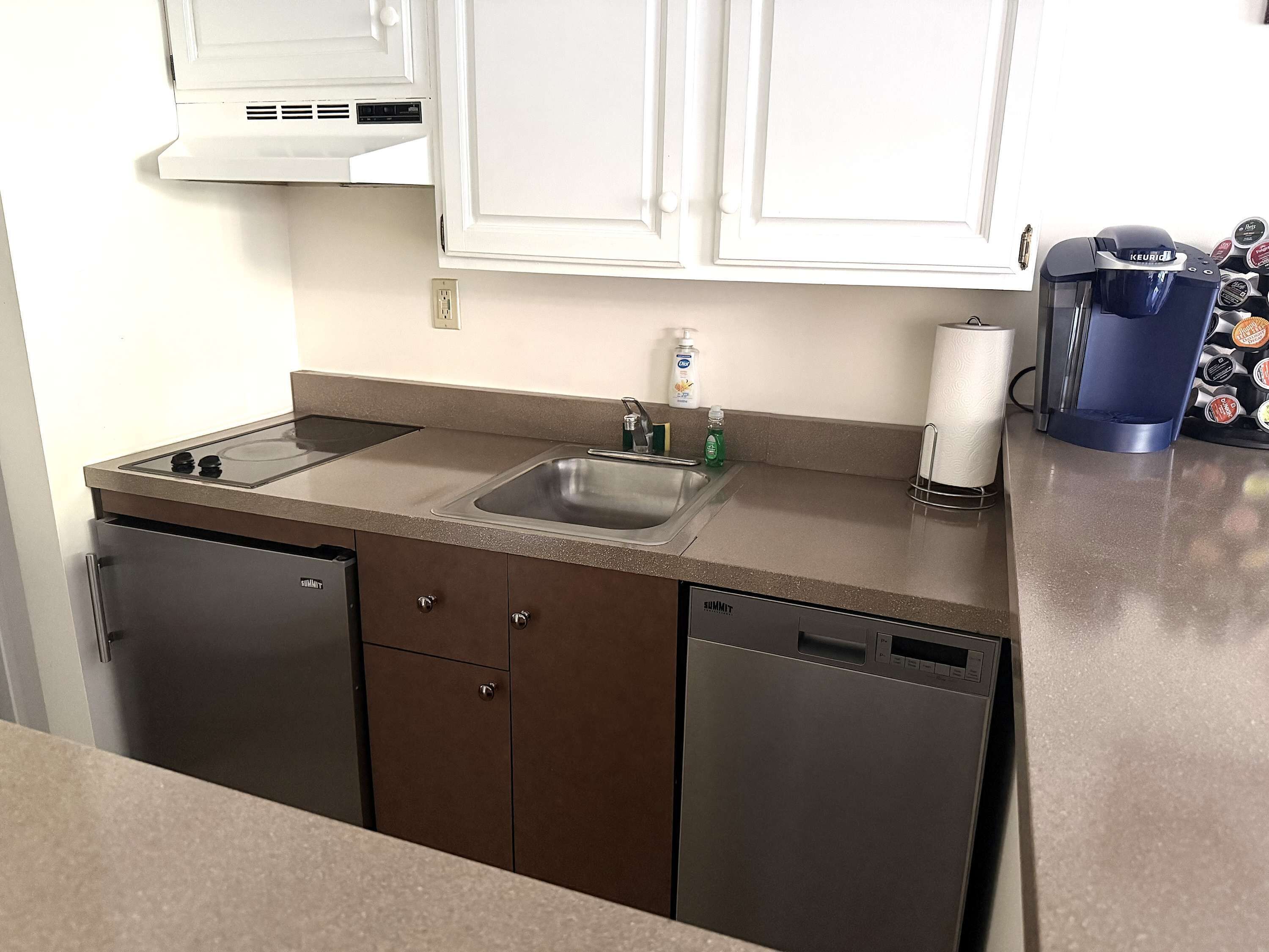 A kitchen with a dishwasher, sink, and a coffee maker.