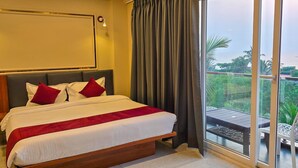 A hotel room with a large bed, a view of the sea, and a balcony with outdoor furniture. - acanoa (Calangute)