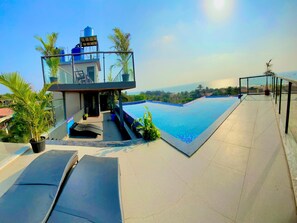 A rooftop pool with a clear view of the ocean, a glass-enclosed structure, and a few potted plants. - acanoa (Calangute)